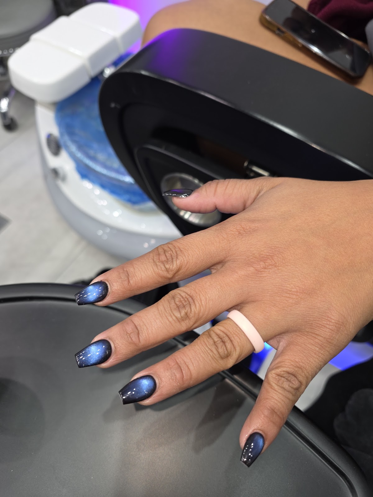 Blue and black chrome ombre nails at a pedicure station