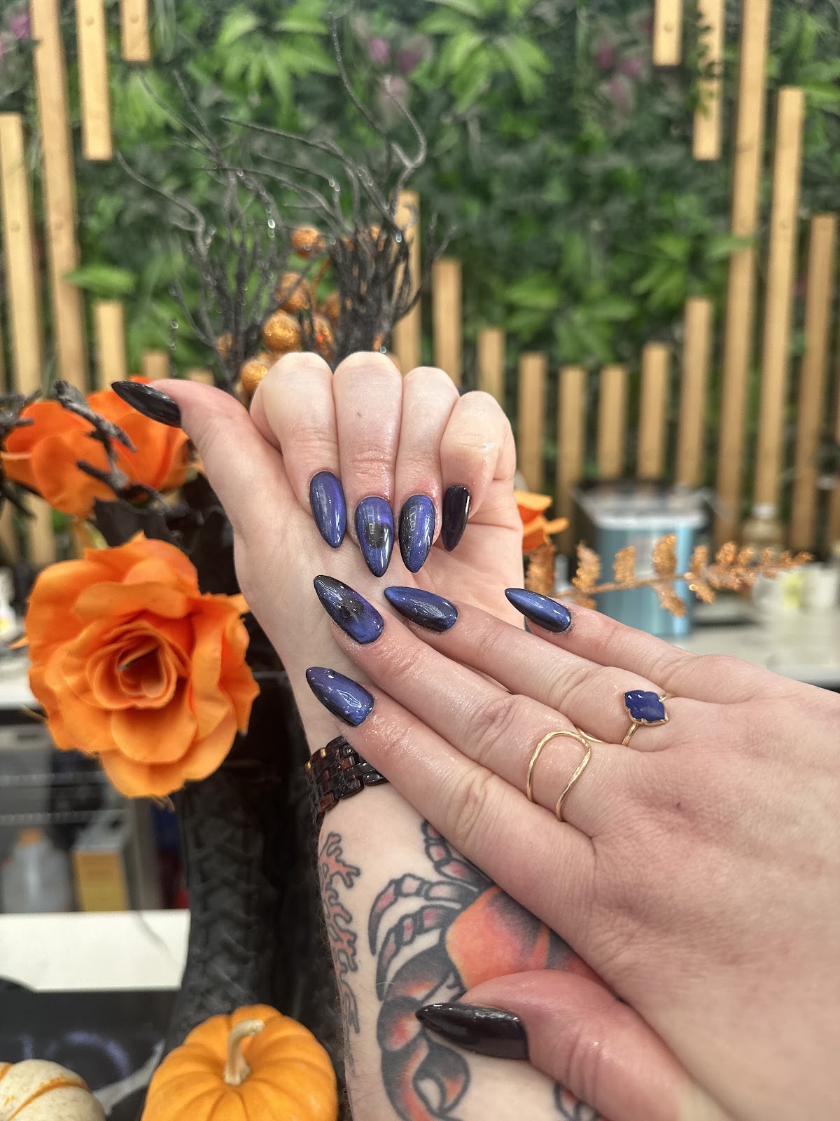 Navy cat eye chrome almond nails with autumn decor in the background